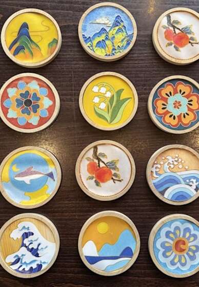 Twelve finished enamel coasters set in their wooden rims